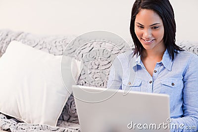 Smiling woman on the couch surfing the internet