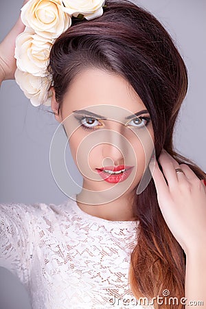 Smiling woman with flowers in head on grey background