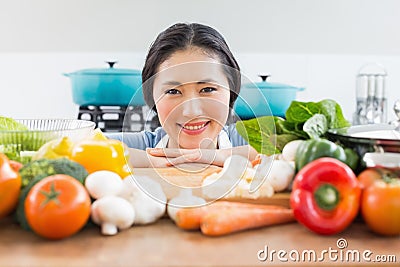 Smiling woman in front of vegetables in kitchen