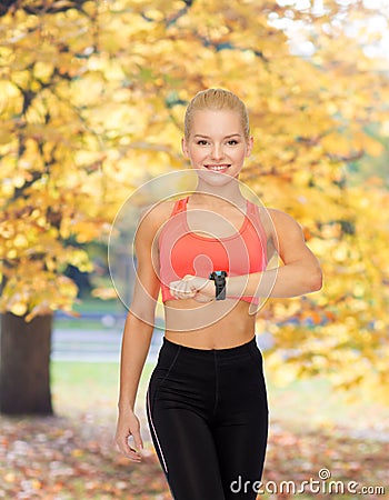 Smiling woman with heart rate monitor on hand