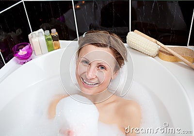 Smiling woman playing in a bubble bath