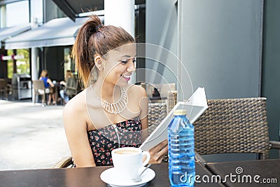 Smiling woman reads book in the terrace restaurant.