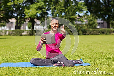 Smiling woman with tablet pc showing thumbs up