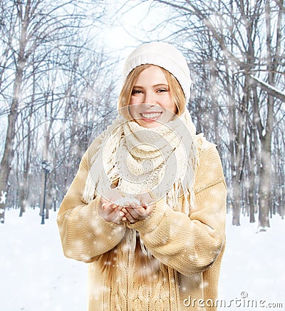 Smiling woman in warm clothing holds snow