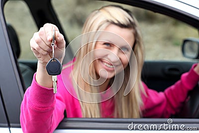 Smiling young female driver showing a key