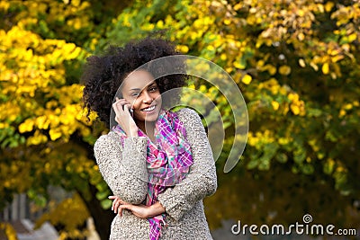 Smiling young woman calling by mobile phone outdoors