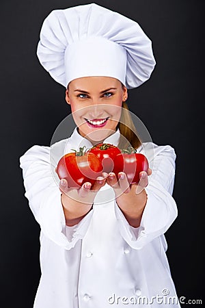 Smiling young woman chef with tomatos juggle