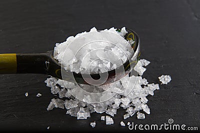 Sea salt flakes, on a wooden spoon and scattered.