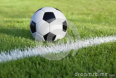 Soccer ball sits on grass field with white stripe