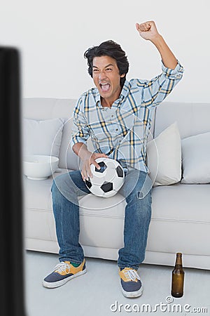 Soccer fan cheering while watching tv