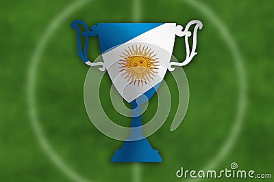 Soccer trophy with Argentina flag inside, field in the background.