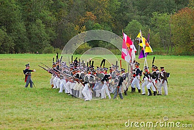 Soldiers in historical costumes march on the battle field with flags.