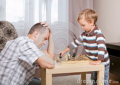 Son and father playing chess at home