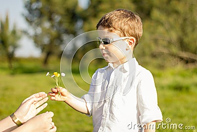 Son giving a bouquet of flowers to his mother in a field