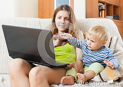 Sorehead woman with baby working with computer