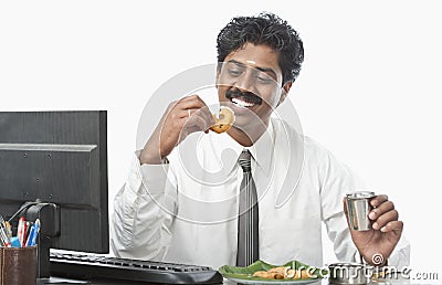 South Indian businessman working in an office and having food
