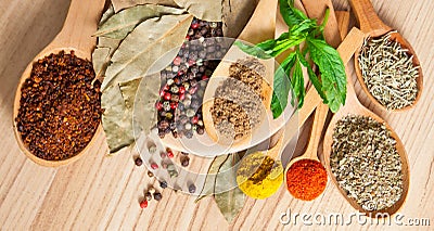 Spices in wooden spoons on brown