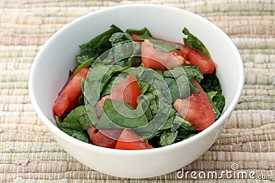 Spinach Tomato Salad with Salt and Coconut Oil in a White Bowl