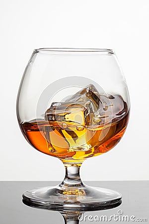 Splash of whiskey with ice in glass on white background