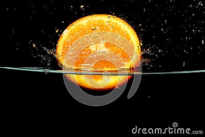 Splashing orange fruit into water