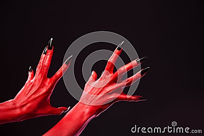 Spooky red devil hands with black nails, real body-art