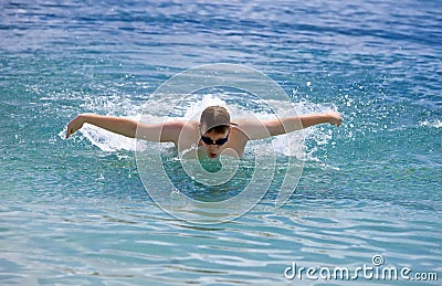 Sporting man swims in the sea butterfly stroke style