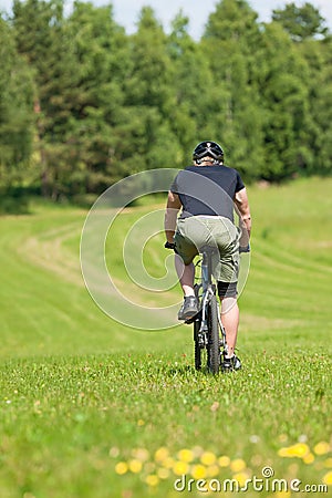 Sportive man mountain biking sunny meadows