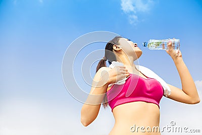 Sporty woman drinking water bottle after jogging or running
