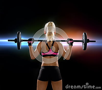 Sporty woman exercising with barbell from back