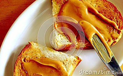 Spreading natural peanut butter on toast