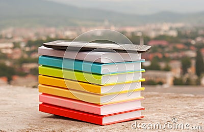 Stack of colorful books with electronic book reade