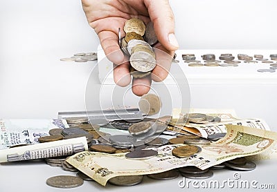 Stack of Indian currency Coins and notes and hand