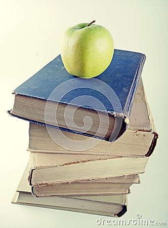 Stack of old hardcover books with green apple