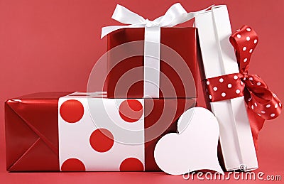 Stack of red and white polka dot theme festive gift box presents with white heart