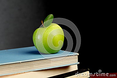 Stack of text books and green apple