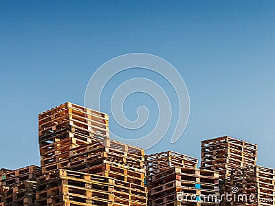 Stacked up pallets against a blue sky