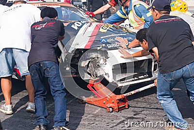 Staff team pushing wrecked racing car