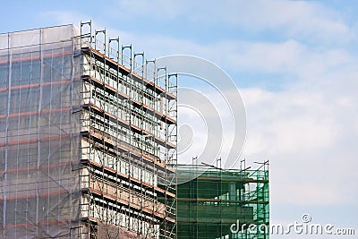 Staircase and scaffolding on a construction site,covered with mesh on sky background.