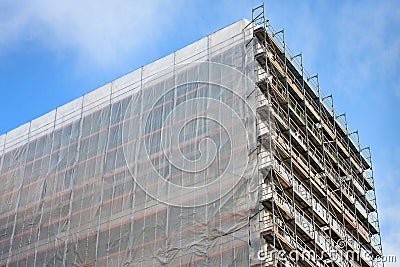 Staircase and scaffolding on a construction site,covered with mesh on sky background.
