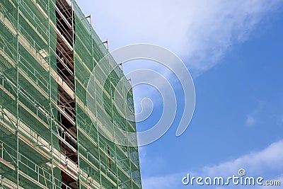 Staircase and scaffolding on a construction site,covered with mesh on sky background.