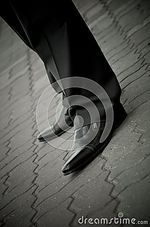 Standing imposing man in a patent leather shoes. legs only