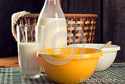 Still life of bottle of milk with glass and two plastic bowls