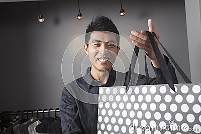 Store clerk holding shopping bag at fashion store
