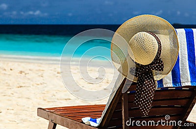 Straw hat on a lounge chair at tropical beach