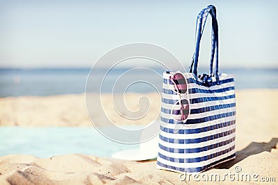 Straw hat, sunglasses and bag lying in the sand