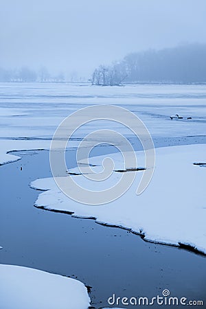 Stream flowing through frozen lake