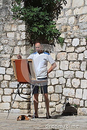 Street artist with an easel and a cat.