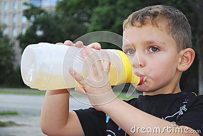 Street boy drinks water from a bottle.