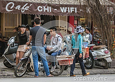 Street scene with young people chatting and food vendor in front