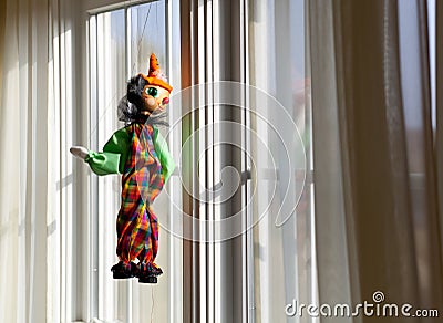 String puppet gazing outside window in sun